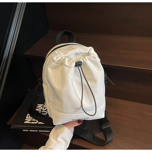 Detail of OOMTAO white canvas drawstring bag with nylon straps on rustic wooden stairs