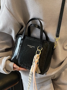 Chic black patent leather bucket bag with textured finish and woven abacus charm