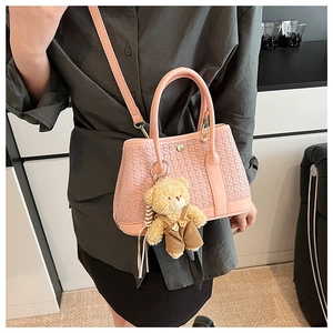 Detailed weave texture on pink crossbody bucket bag with cute bear charm accessory
