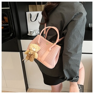 Detailed texture of pink woven bucket bag featuring a cute teddy bear plush charm