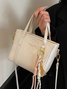 Minimalist cream white bucket bag with golden hardware and stylish tassel charm for women