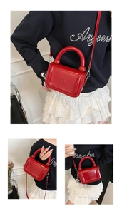 Détail du mini sac en cuir verni rouge avec poignées perlées et finitions argentées