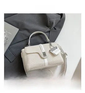 Detail der cremeweißen gewebten Handtasche mit Metalldrehverschluss und breitem Schultergurt
