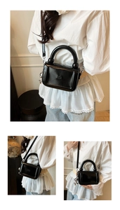 Détail du sac à main noir brillant avec poignée arquée et pendentif chien ballon argenté