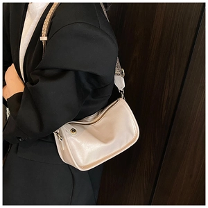 Détail d'un sac crème avec des clous en métal vintage et une large bandoulière tissée