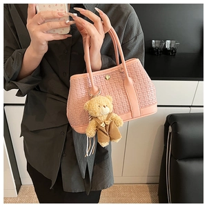 Detailed texture of pink woven bucket bag featuring a cute plush bear charm