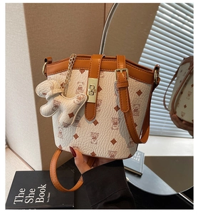 Detailed view of cream-colored bucket bag with bear print and golden twist lock