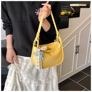 Detail of yellow lychee leather shoulder bag with metal lock and doll pendant decor