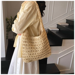 Detailed close-up of a hollow woven straw tote bag texture and large shoulder strap design