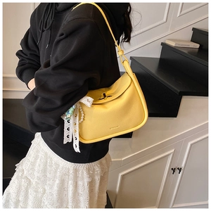 Detail of yellow pebble leather pillow bag with lace, pearls and metal turn-lock buckle