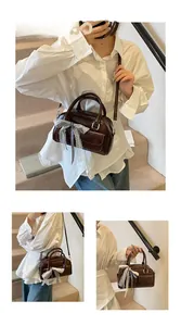 Detail of dark brown bow bowling bag with lace texture and side pocket shown on model