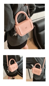 Gros plan sur un sac rose brillant avec pendentif lapin argenté et poignée ronde