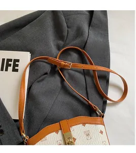 Close-up of the adjustable leather strap and golden metal buckle on a patterned bucket bag