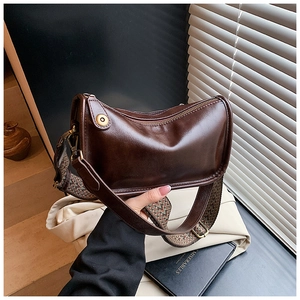 Détail d'un sac demi-lune marron foncé avec bandoulière tissée et boucle en laiton
