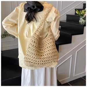 Detail of hand-woven hollow knit pattern on beige straw tote bag for beach vacation