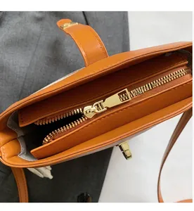 Detail view of the smooth golden metal zipper and pebble leather texture on a bucket bag