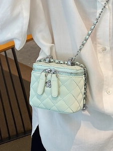 Mint green quilted vanity bag with chain strap and camellia charm shown on a model