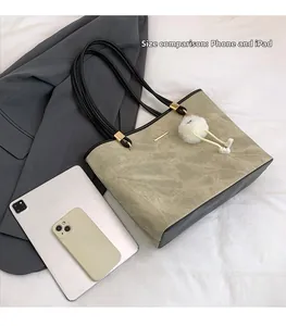 Detailed view of olive khaki tote bag with vintage texture and plush charm accessory