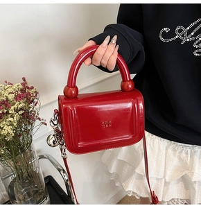 Détails de ce sac à main en cuir verni rouge brillant avec chaîne argentée et pendentif