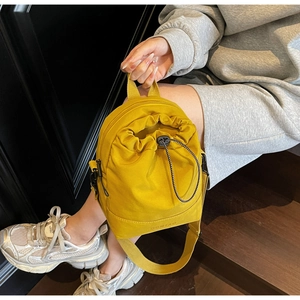 Detail view of yellow canvas drawstring bag featuring brand embossing and black woven cords