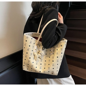 Detail of printed tote bag with bear pattern and dog charm over the shoulder