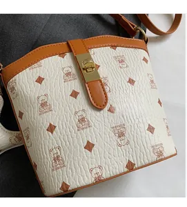 Close-up of bear pattern and diamond motif on white lychee grain leather bucket bag