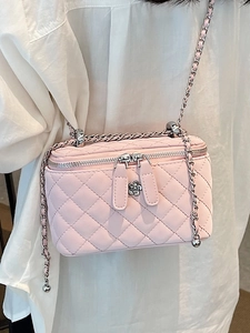 Pink quilted chain crossbody bag with floral zipper pulls shown on model shoulder