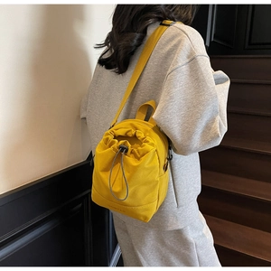 Detail of a bright yellow canvas drawstring bag featuring textured fabric and DONTAS logo