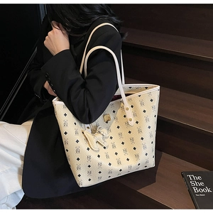 Detailed close-up of a cream tote bag with bear print and golden logo plate