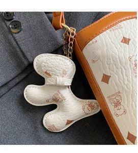 Detail of the white leather bucket bag with bear print and golden metal chain charm