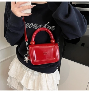Gros plan sur le sac rouge brillant avec breloque lapin argentée et poignée ronde unique
