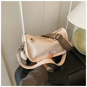 Détail du sac en cuir crème avec une large bandoulière tissée de style ethnique