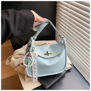 Close-up of light blue pebbled leather handbag featuring a gold-tone twist lock and pearl charm