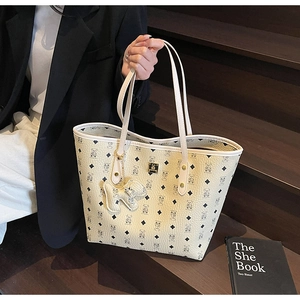 Detail of light beige tote bag with bear print pattern and golden nameplate on stairs