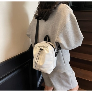 Detail of white nylon drawstring crossbody bag with black adjustable strap and brand logo