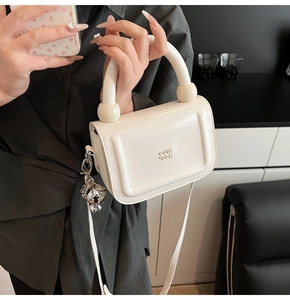 Gros plan détaillé d'un petit sac à main blanc carré avec breloque d'ours en métal