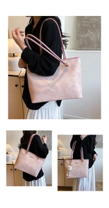 Close-up of pink suede tote bag featuring metallic logo detail and fuzzy pompom charm