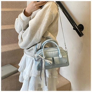 Détail du sac Boston bleu clair avec poches avant et breloque en dentelle de nœud