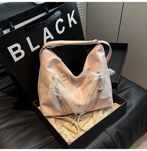 Detailed macro view of pink glossy tote with lace edges and pearl bow charms in a gift box