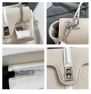 Detailansicht der Strohtasche mit silbernem Drehverschluss, Jacquard-Gurt und Taschenanhänger