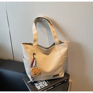 Close-up of beige tote bag texture with cute teddy bear charm on urban housing books