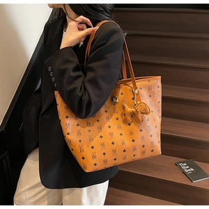 Detailed macro of cognac brown tote bag featuring bear print and puppy charm