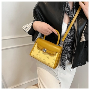 Close-up of yellow embossed Kelly bag with cartoon bear patterns and silver rotating metal lock