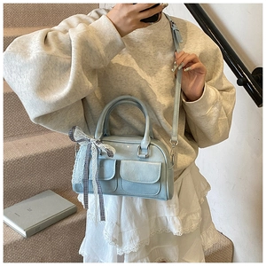 Détail du sac Boston bleu clair avec poches à rabat et breloque nœud à carreaux