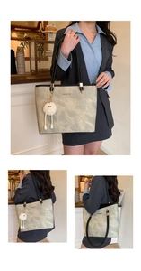 Detail of grey stone-patterned tote bag with black straps and plush doll charm