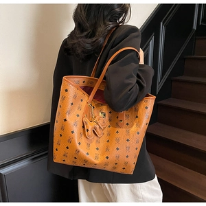 Detail view of stylish brown tote bag with bear print pattern and cute dog charm pendant