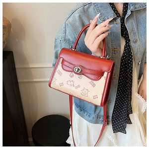 Dettaglio della mini borsa rossa e crema con stampe cartoon e chiusura girevole in metallo