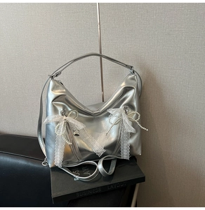 Detail of silver balletcore tote bag featuring white lace bows and pearl decorations