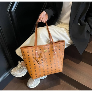 Detailed close-up of a cognac tote bag with monogram print and a cute bear charm accessory