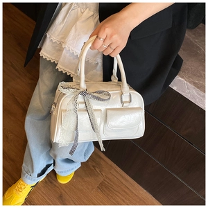 Détail du sac Boston blanc avec nœud en dentelle et boucles en métal argenté